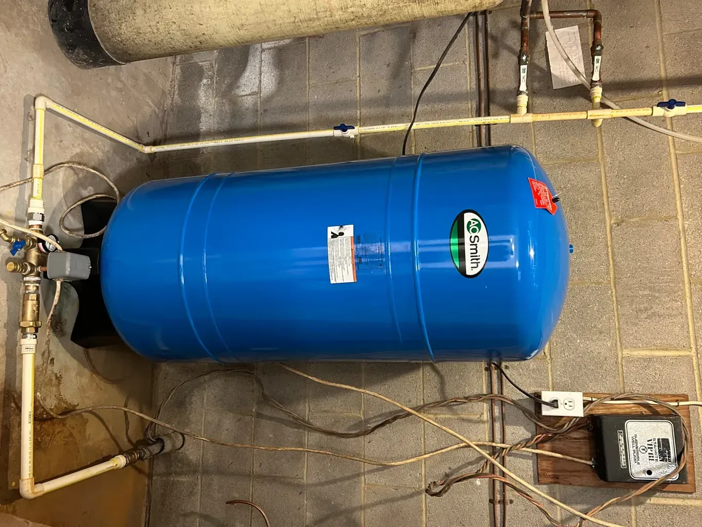 A blue water tank is sitting on top of a concrete wall.