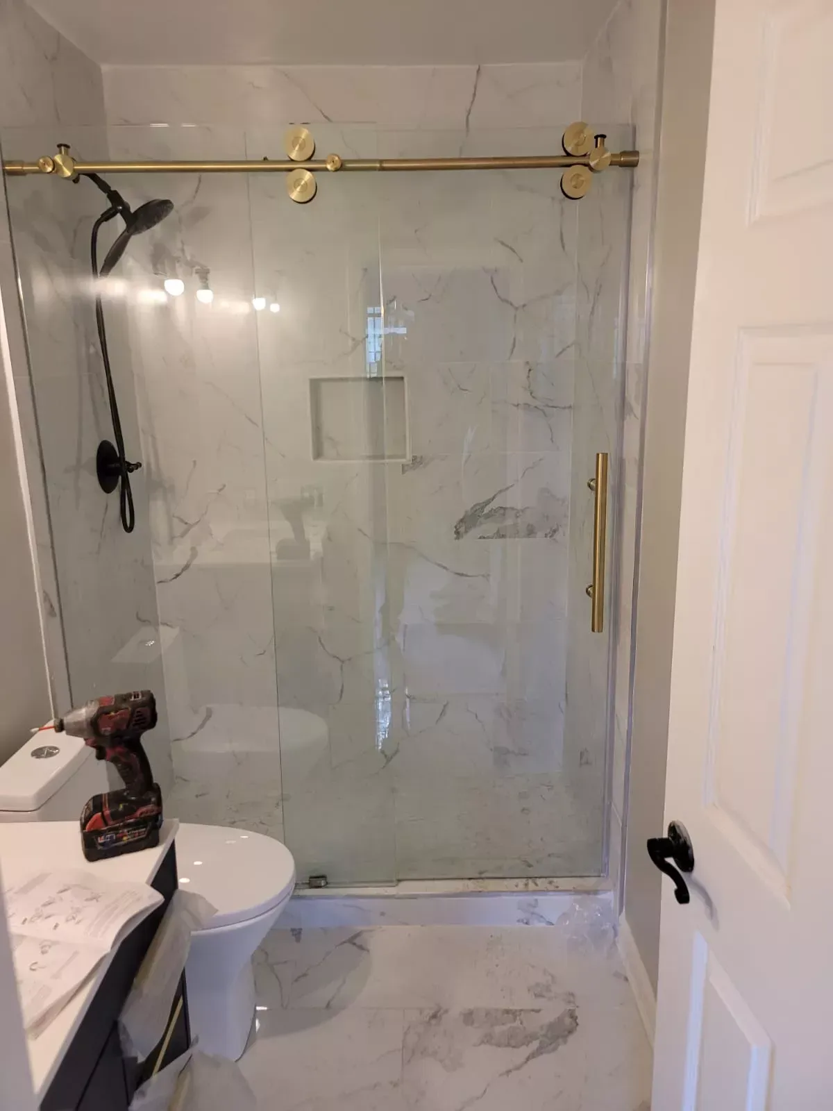 A bathroom with a toilet , sink , shower and sliding glass door.