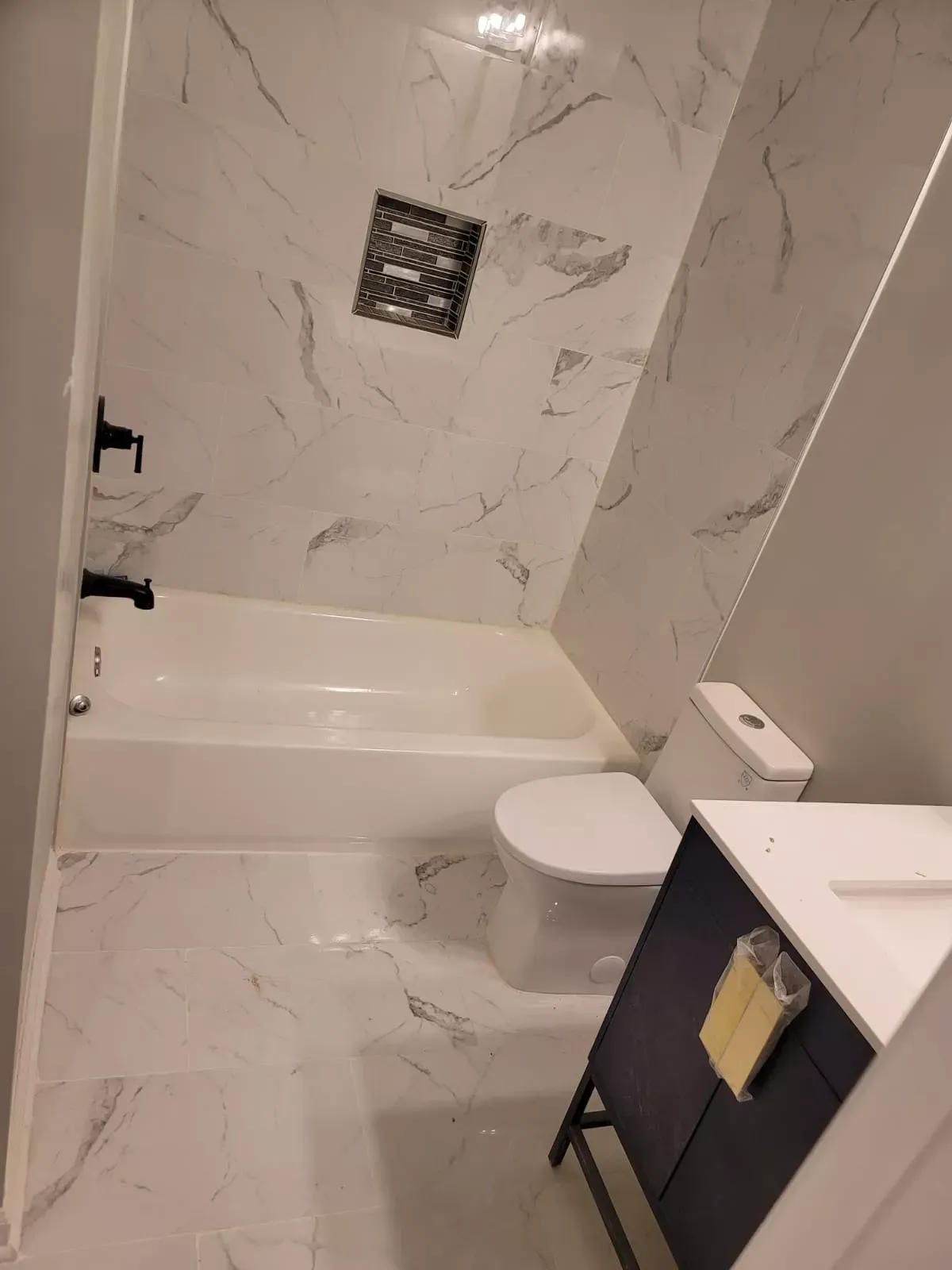 A bathroom with a tub , toilet , sink and mirror.