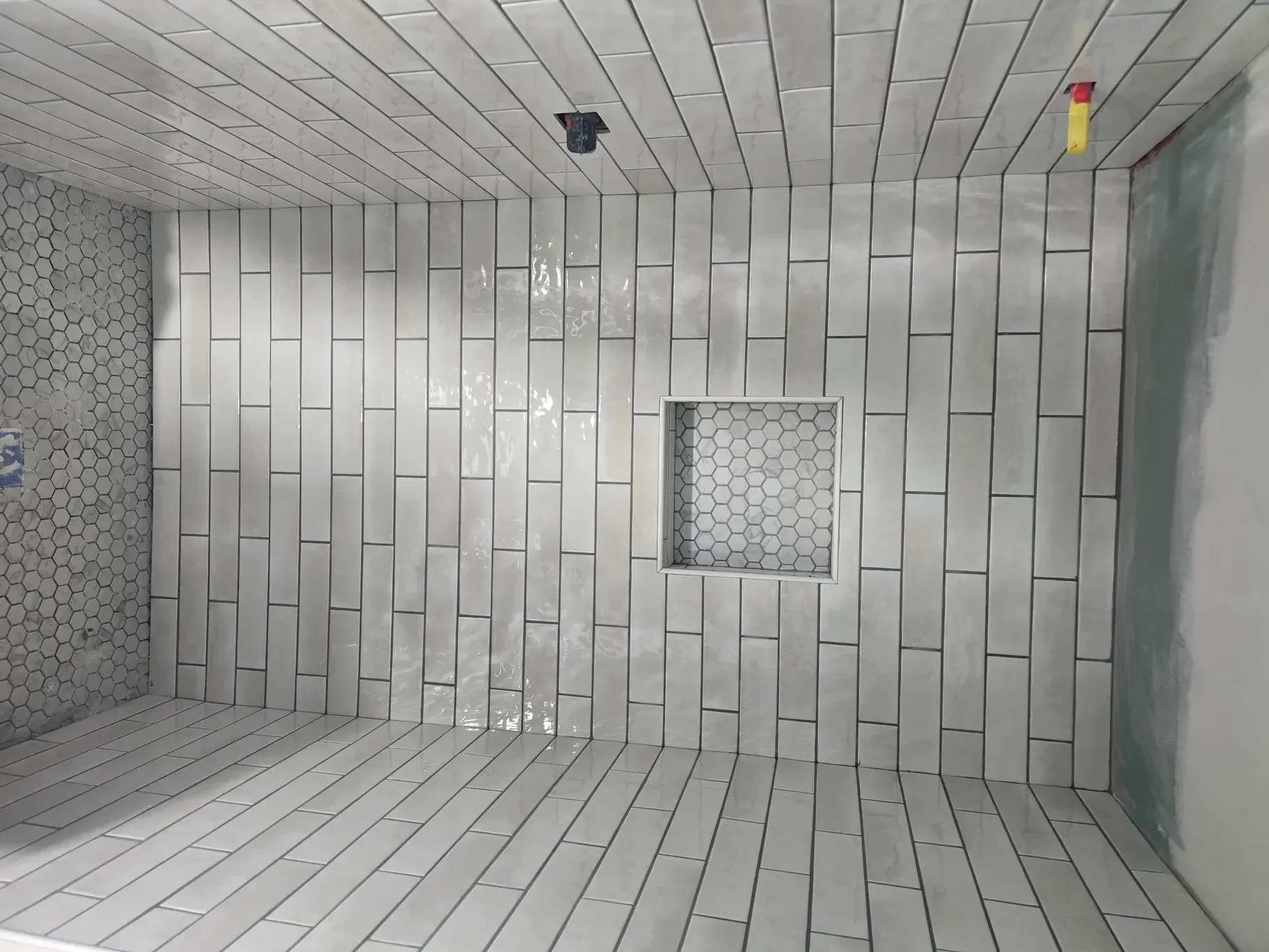 A bathroom with white tiles on the walls and floor.