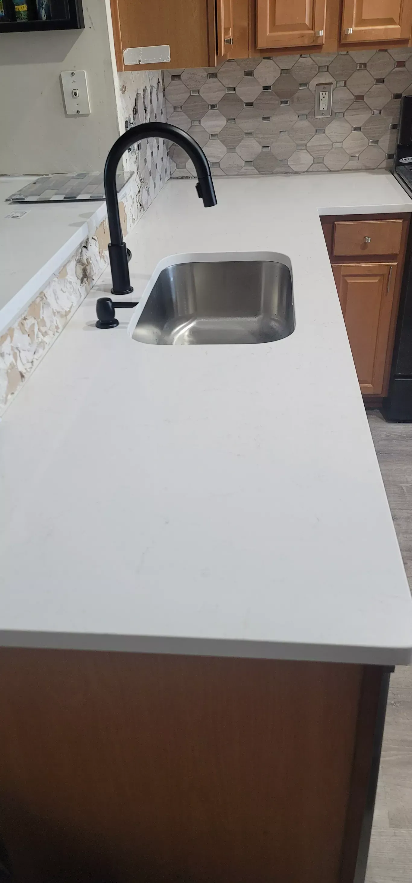 A kitchen with a stainless steel sink and a black faucet.