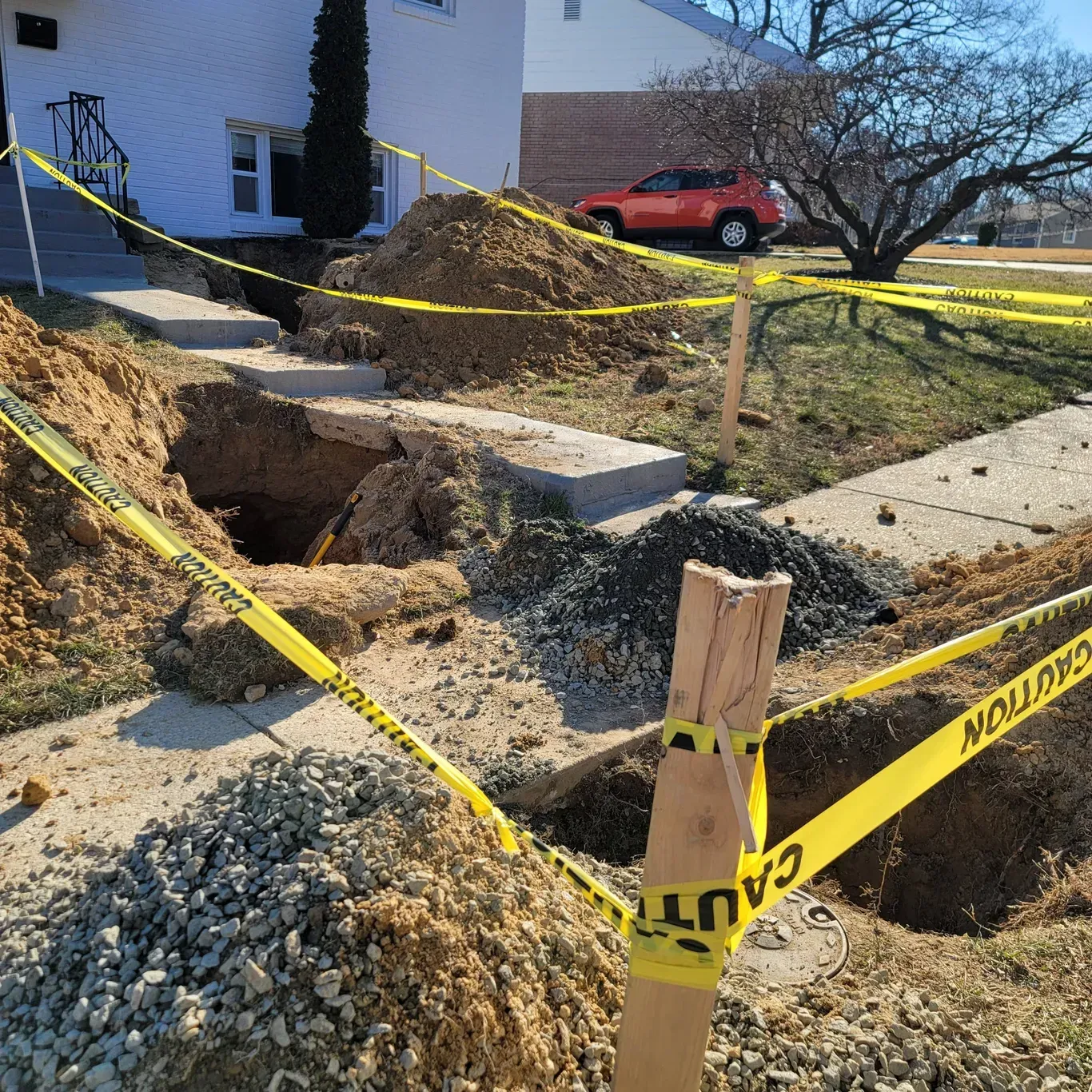 A yellow caution tape surrounds a hole in the ground