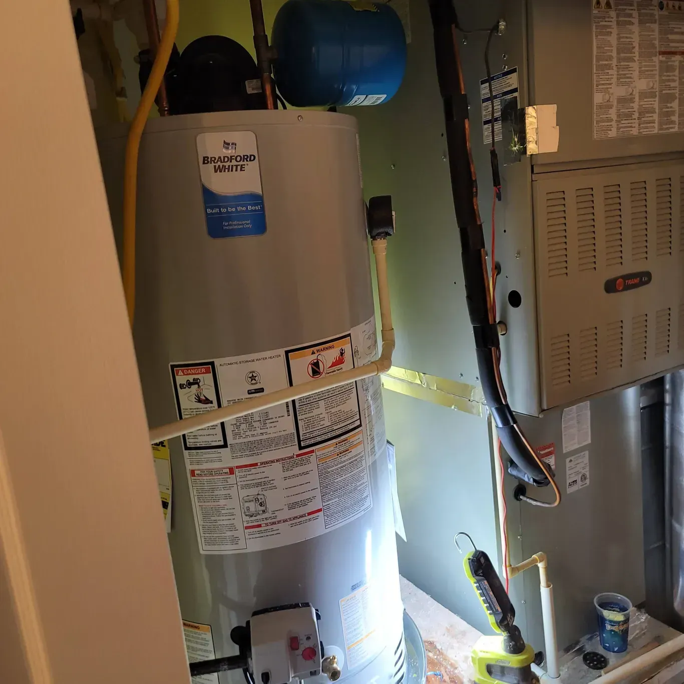 A water heater is sitting in a room next to an air conditioner.