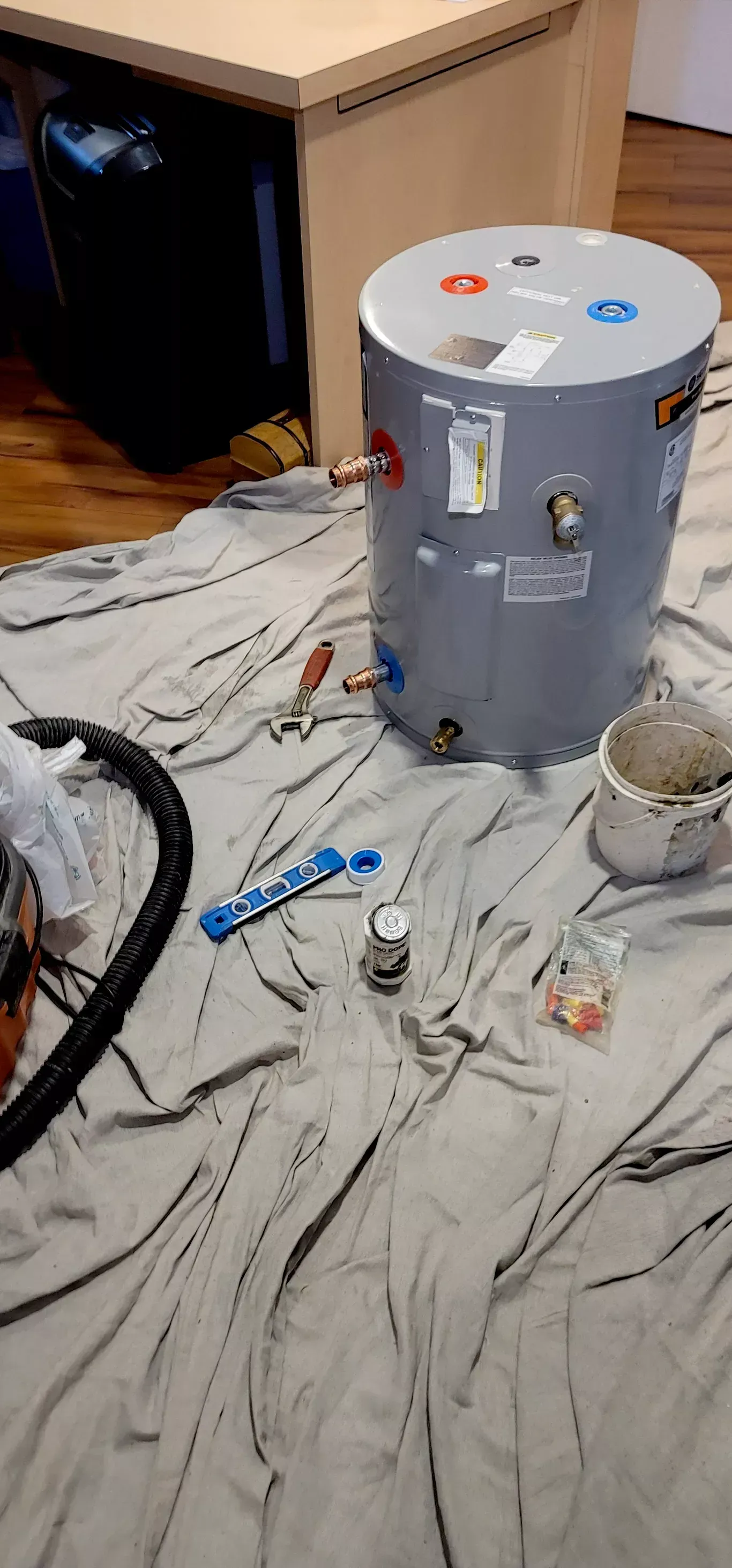 A water heater is sitting on a blanket on the floor.
