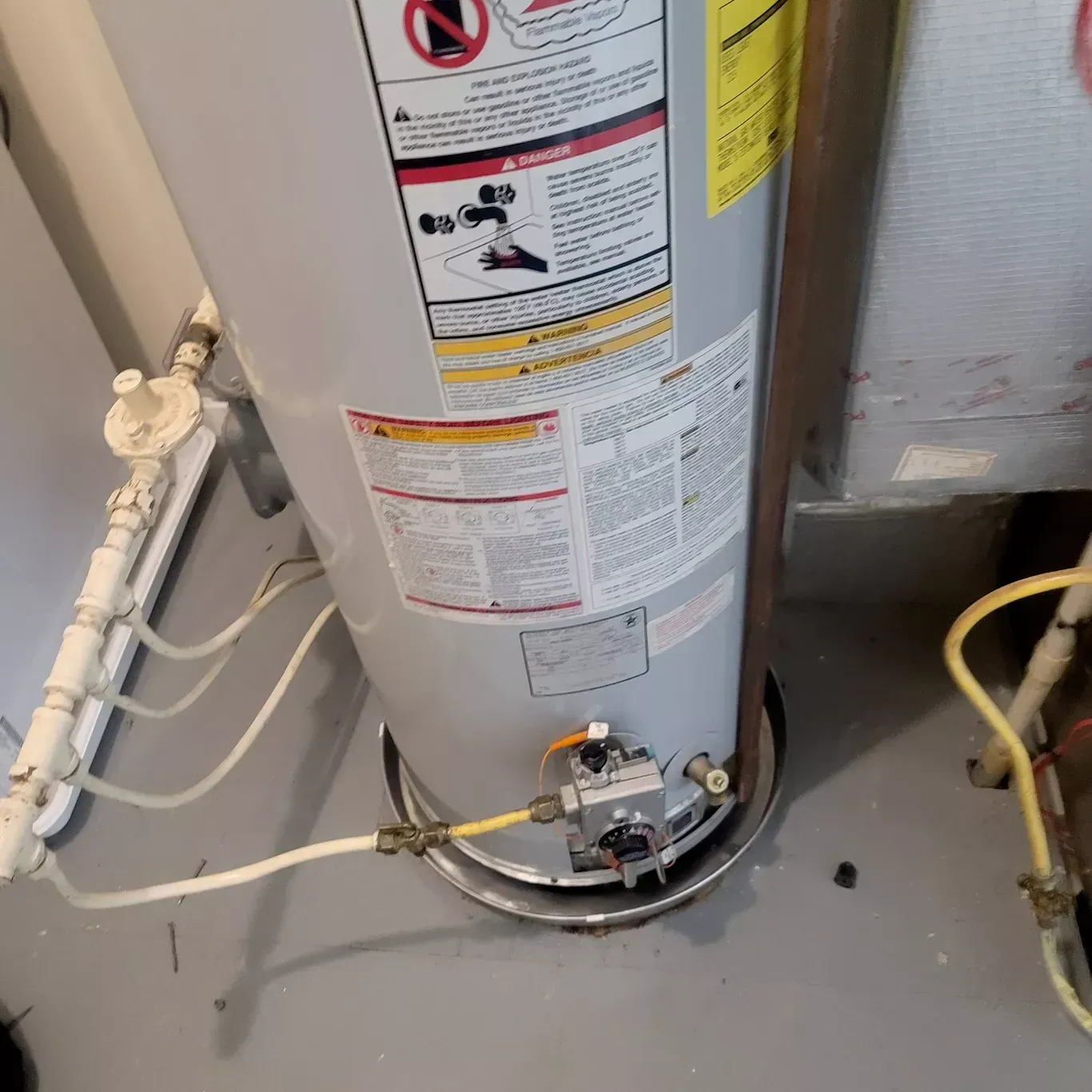 A gas water heater is sitting on the floor in a room.
