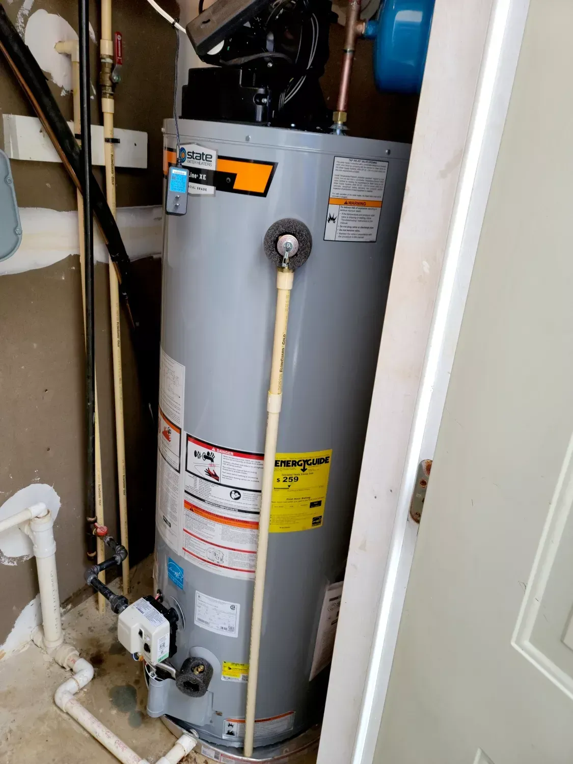 A water heater is sitting in a closet next to a door.