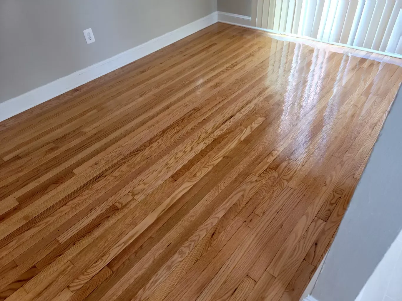 A living room with hardwood floors and a window.