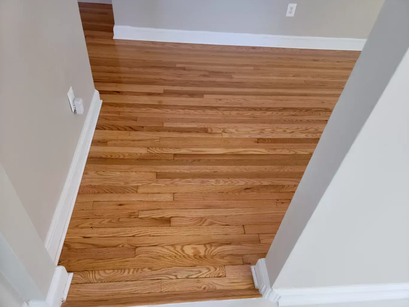 A hallway with hardwood floors and white trim