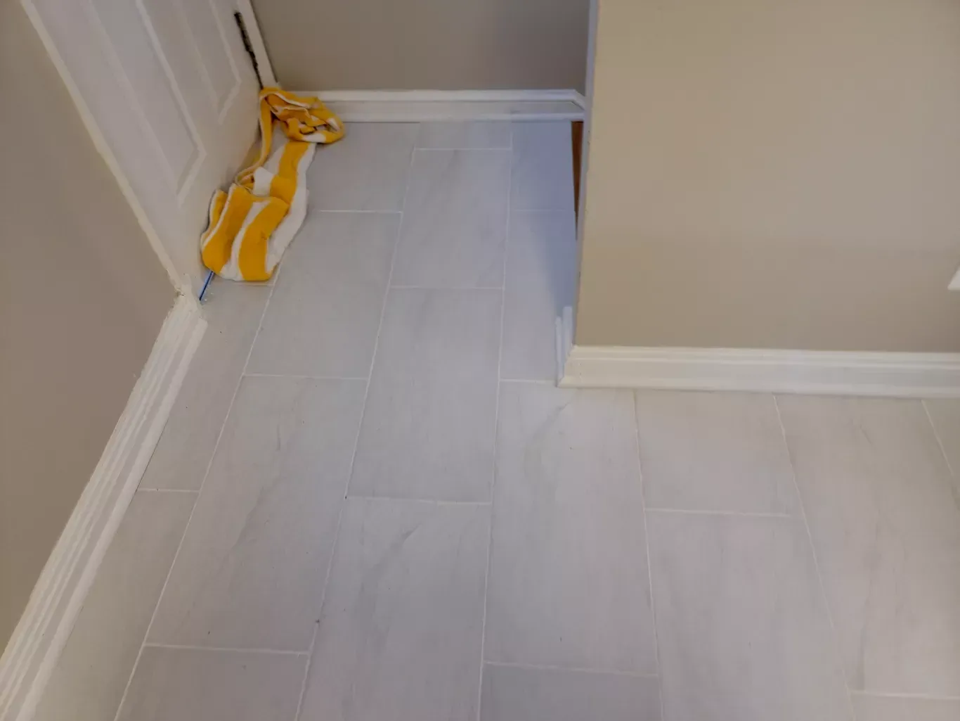 A mop is sitting on the floor of a bathroom next to a door.