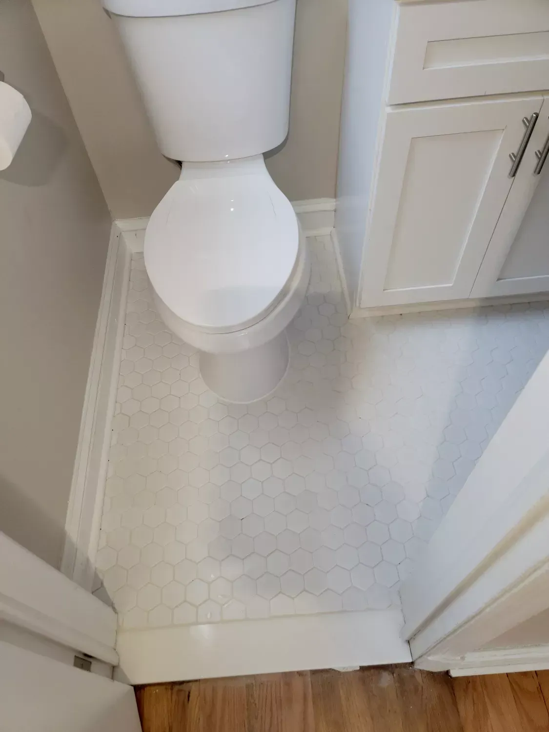 A bathroom with a toilet , sink , and cabinets.