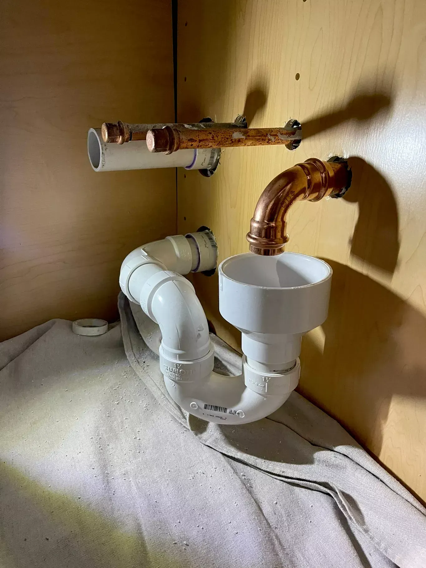A sink with a drain pipe and a copper pipe underneath it.