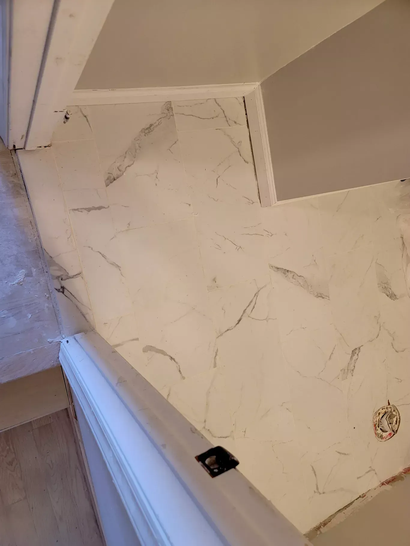 A white marble floor is being installed in a bathroom.