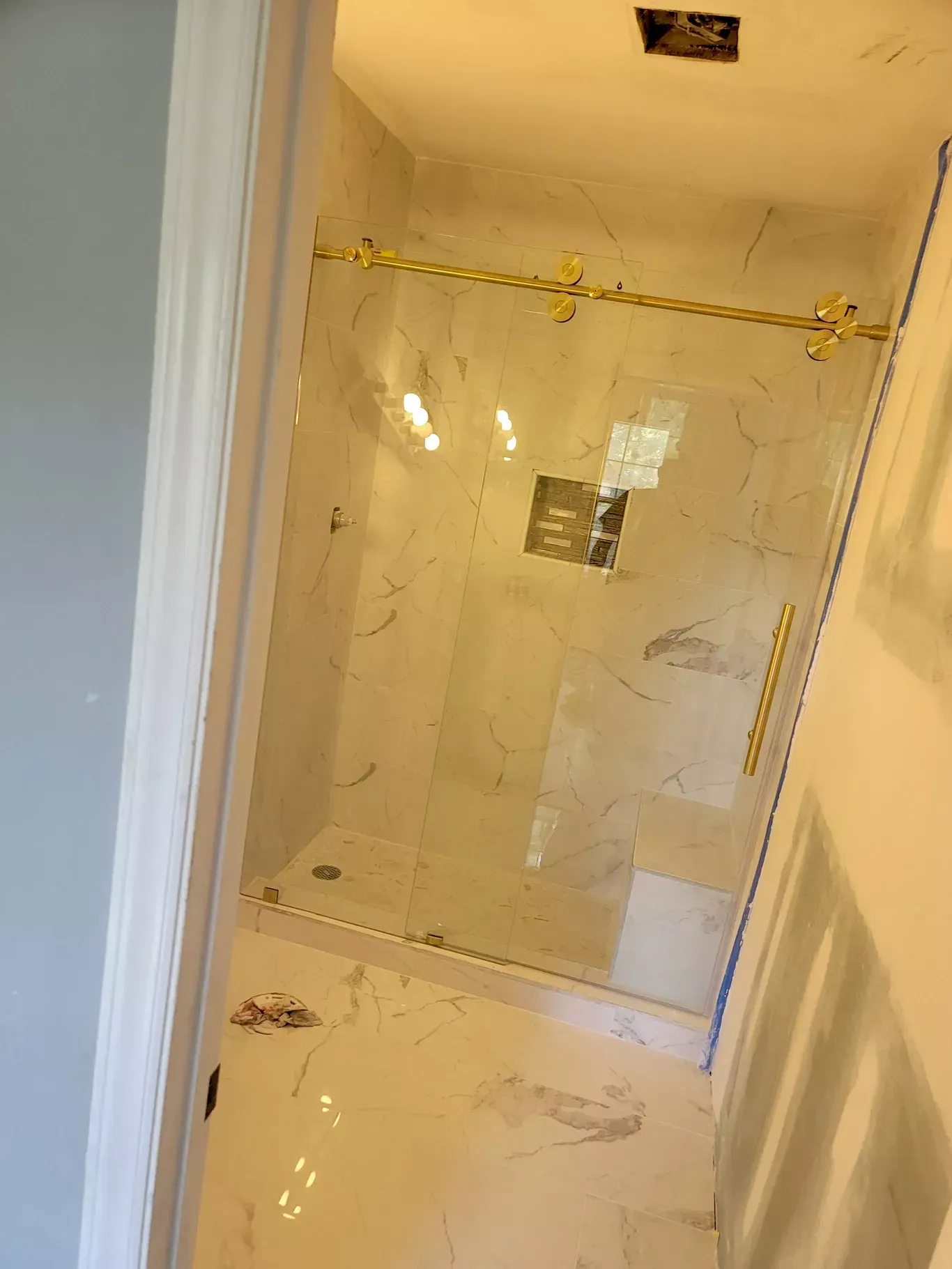 A bathroom with a walk in shower and a marble floor.