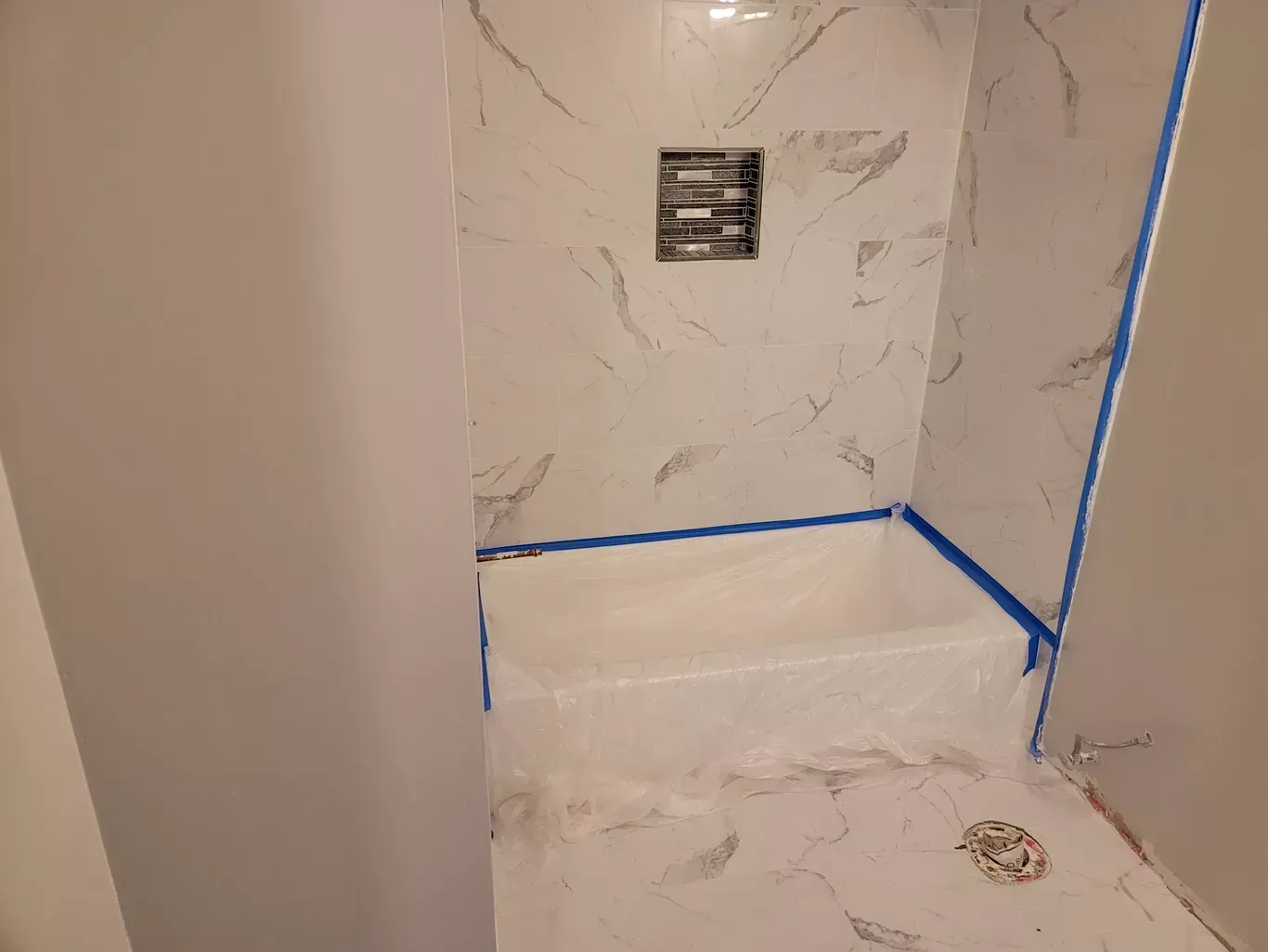 A bathroom with marble tiles and a bathtub.