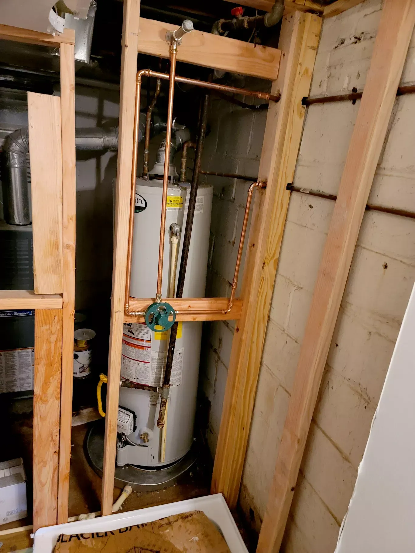 A water heater is sitting in a corner of a room.