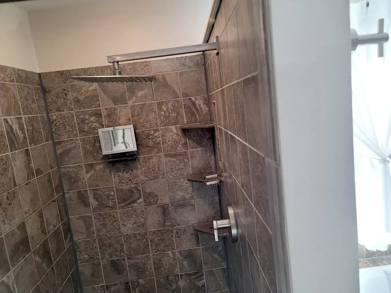 A bathroom with a walk in shower and a shower head.