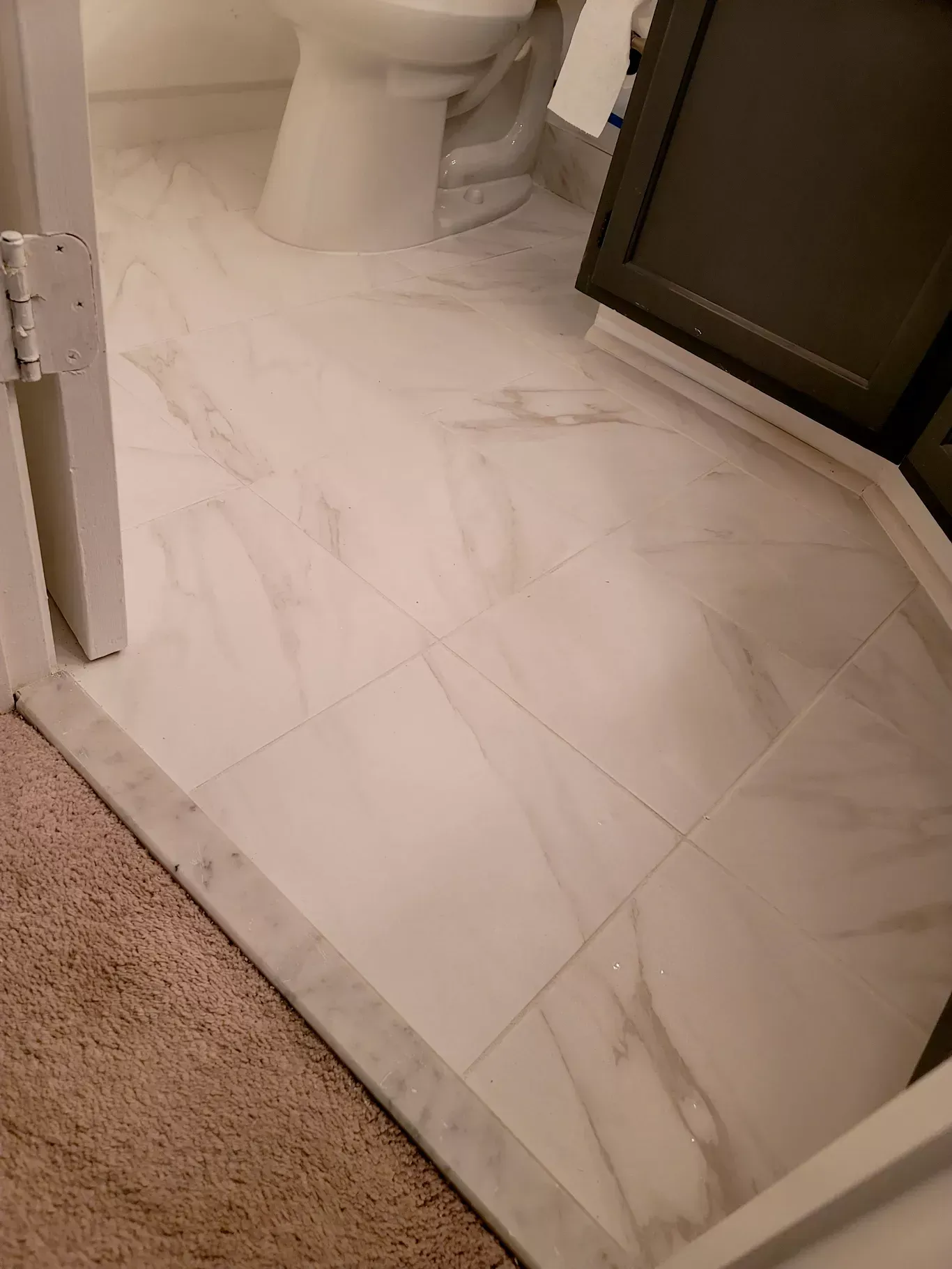 A bathroom with white tile floors and a toilet.