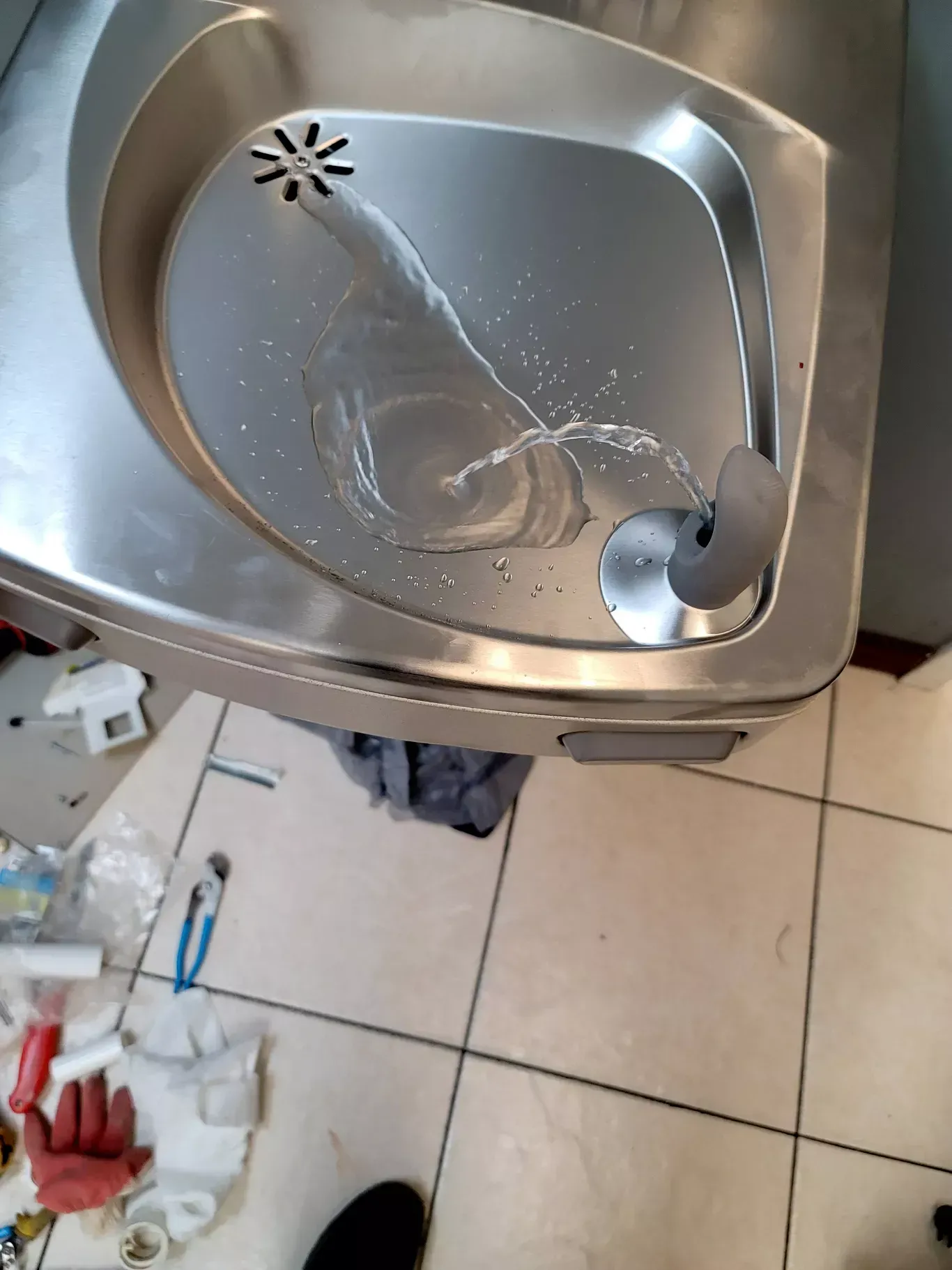 A stainless steel sink with water coming out of it