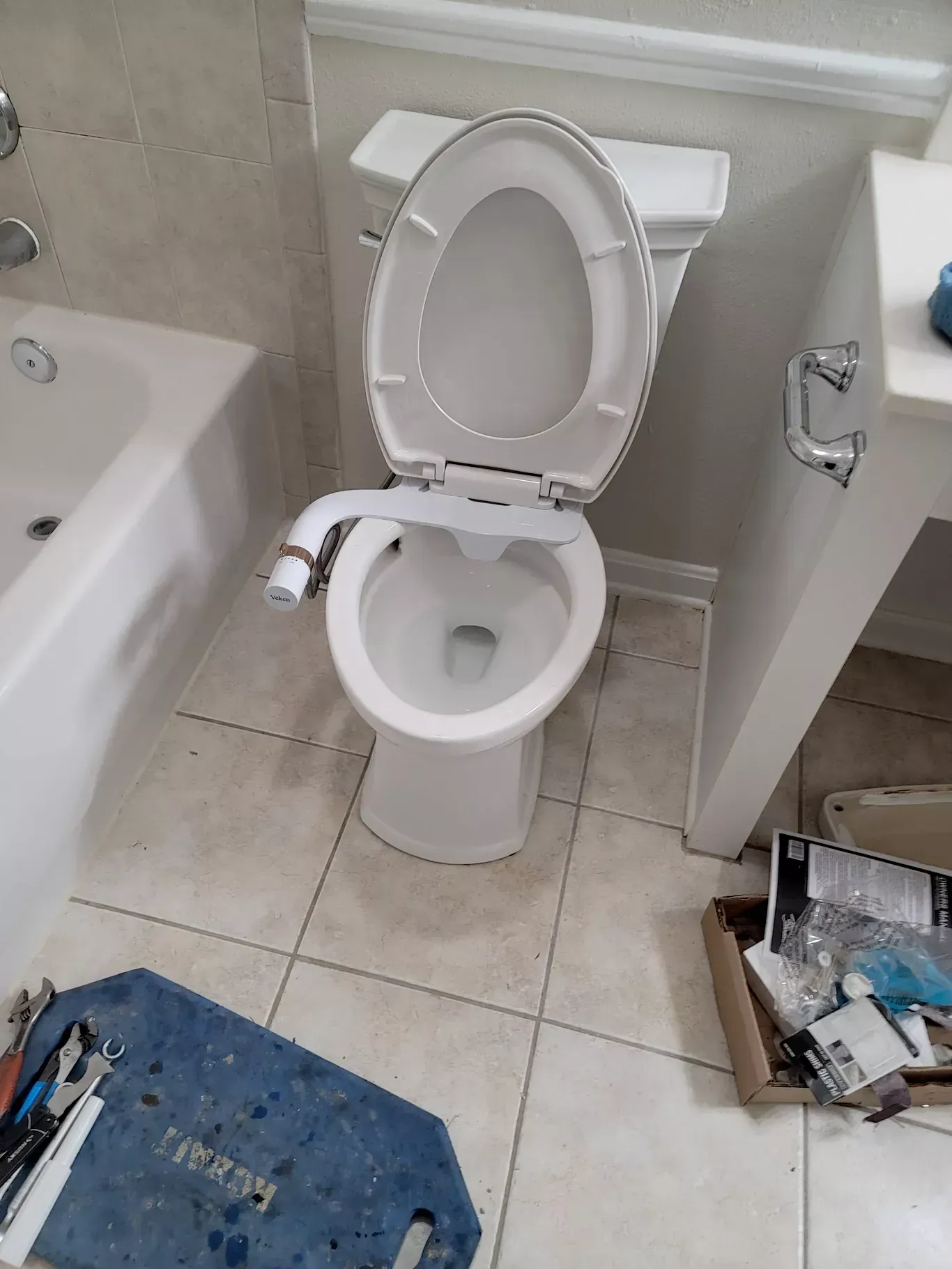 A toilet is sitting in a bathroom next to a bathtub.