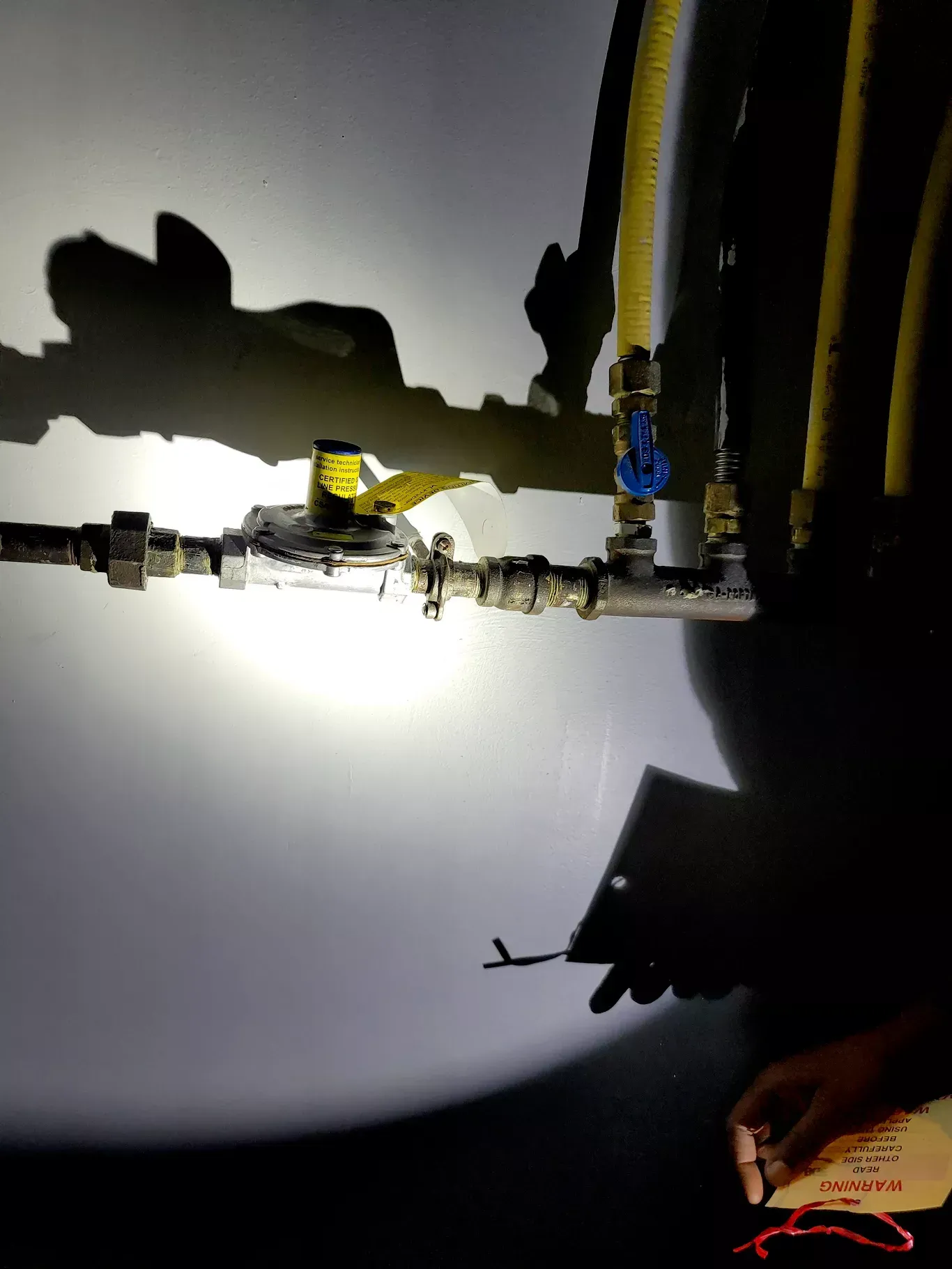 A person is writing on a piece of paper in front of a gas pipe.