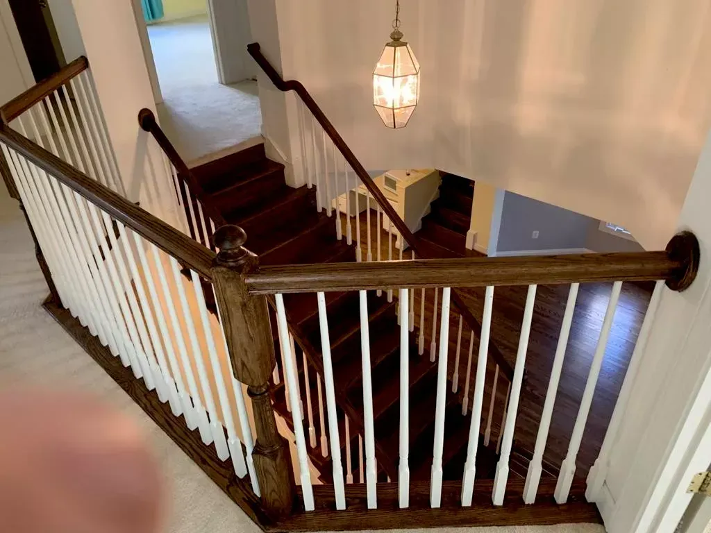 A wooden staircase with white railings and a chandelier hanging from the ceiling.
