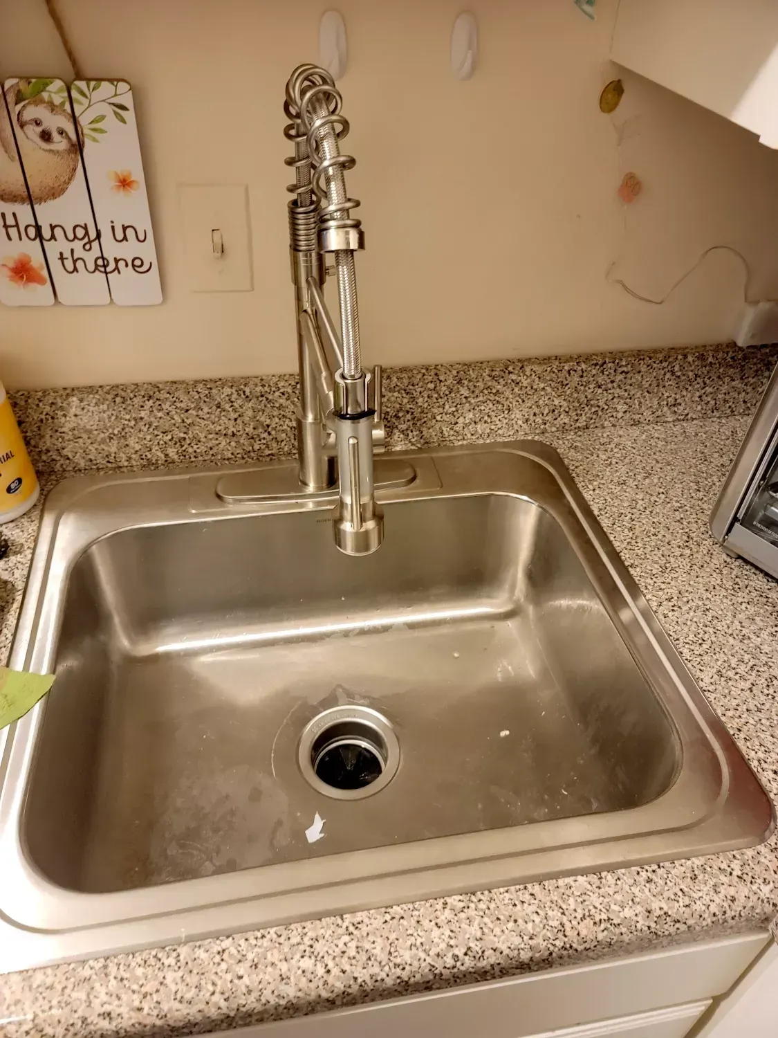 A stainless steel kitchen sink with a faucet on a granite counter top.