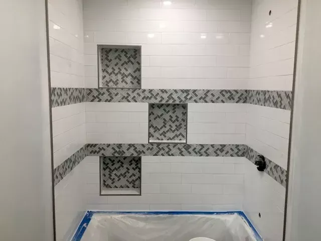 A bathroom with white tiles and a toilet.