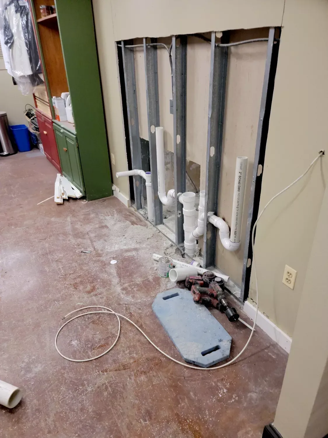 A room with a hole in the wall and pipes coming out of it.