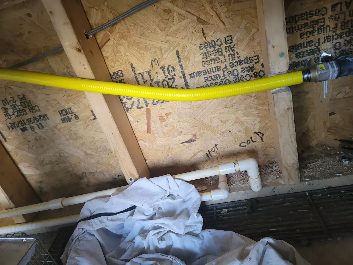 A yellow pipe is hanging from a wooden wall.