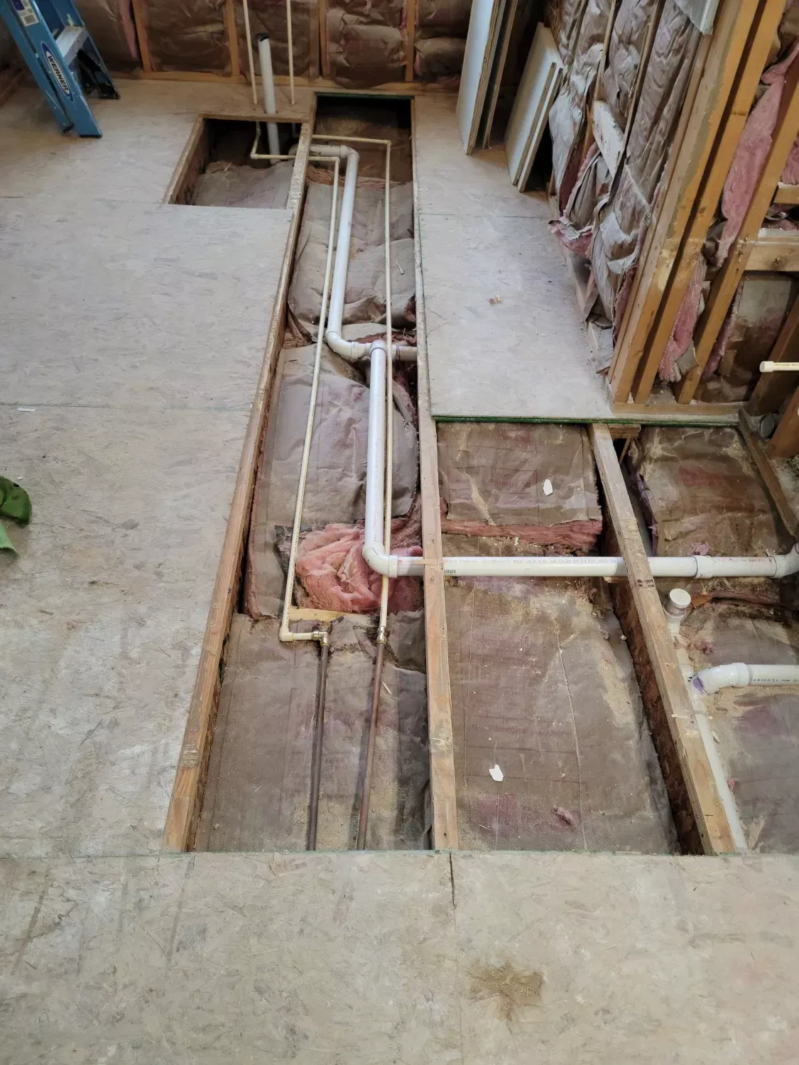 A room with a lot of pipes in it and a ladder in the background.