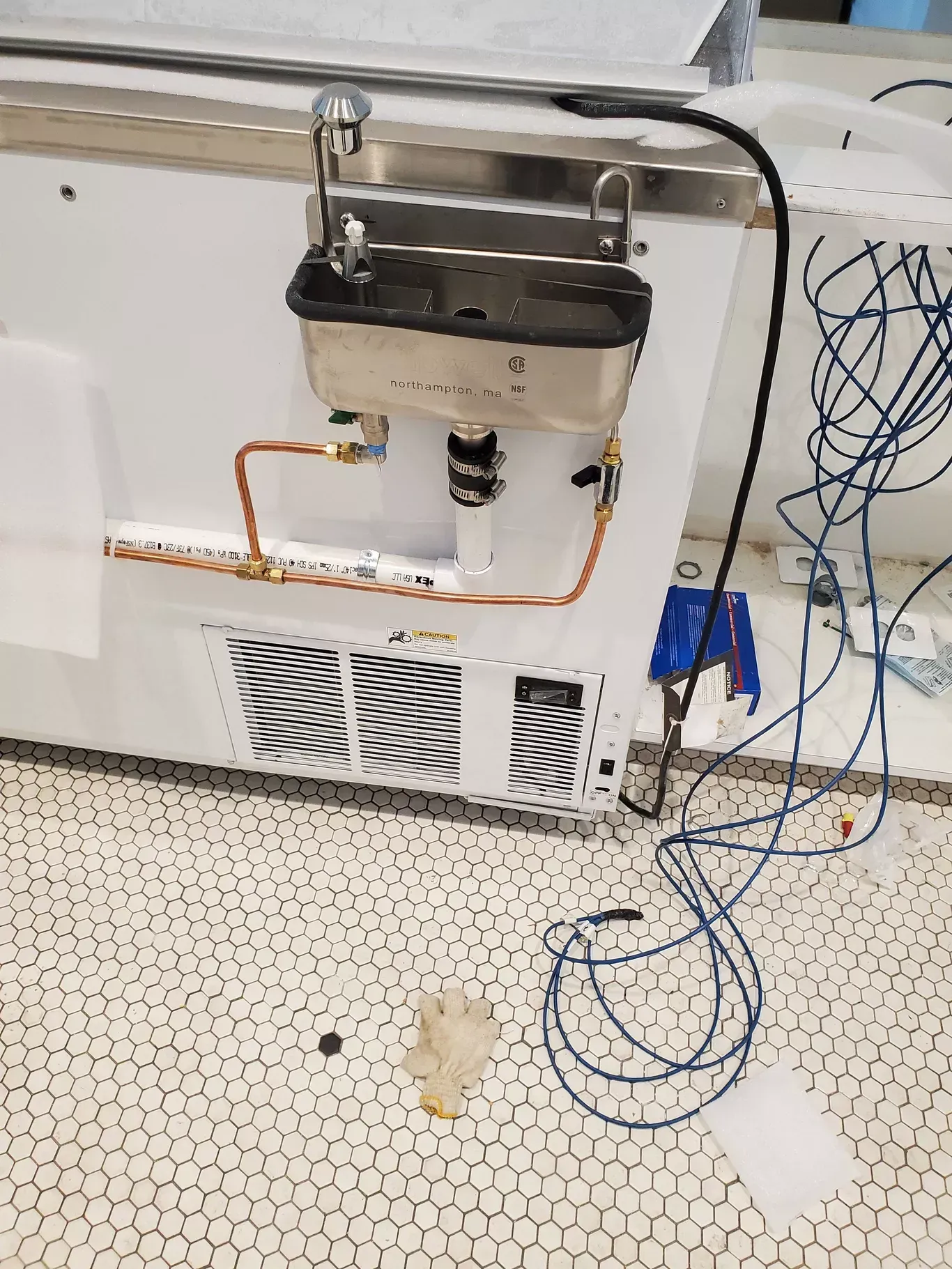 A stainless steel sink is being installed on the side of a refrigerator.