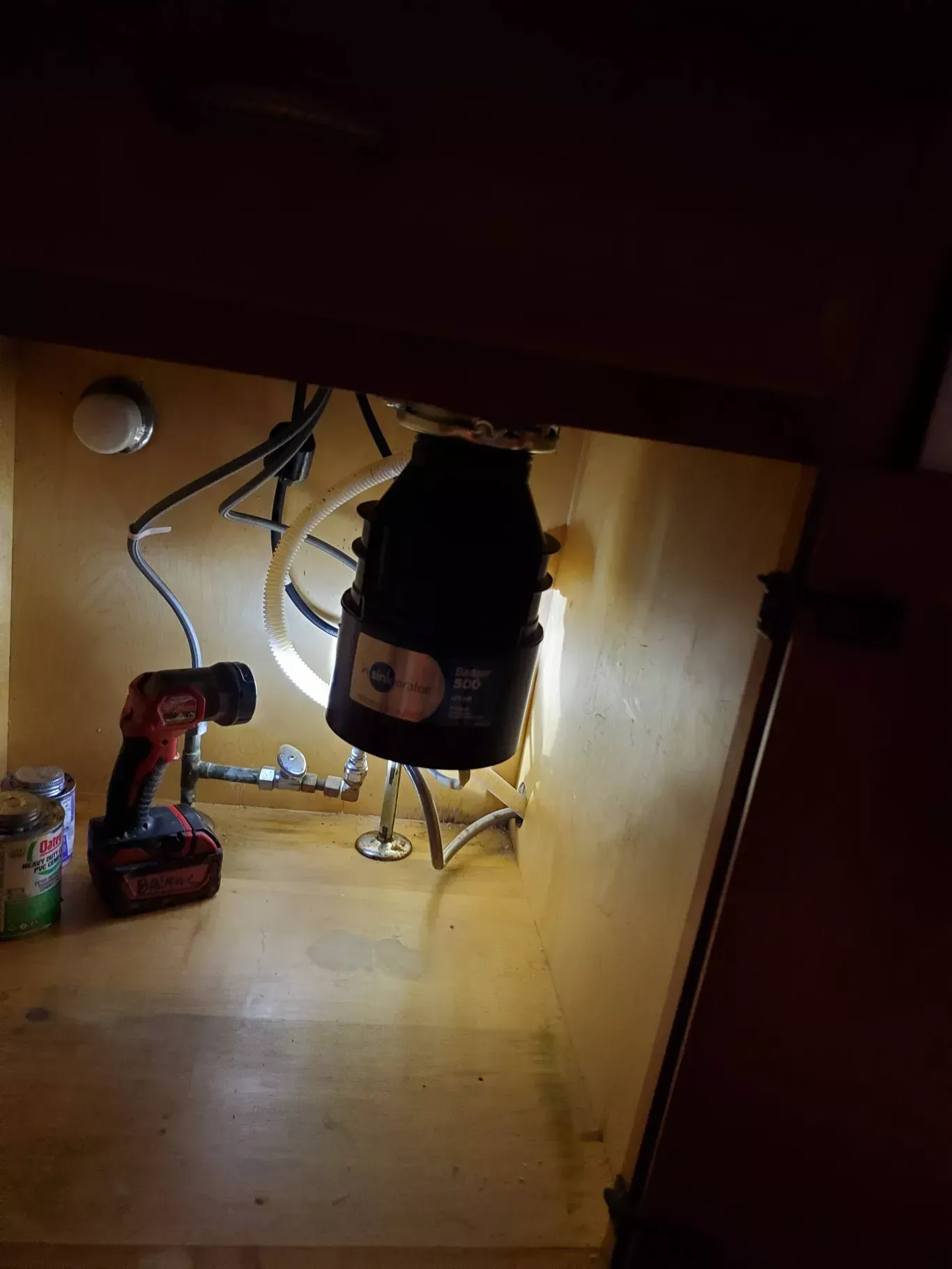 A garbage disposal is being installed under a sink in a kitchen.