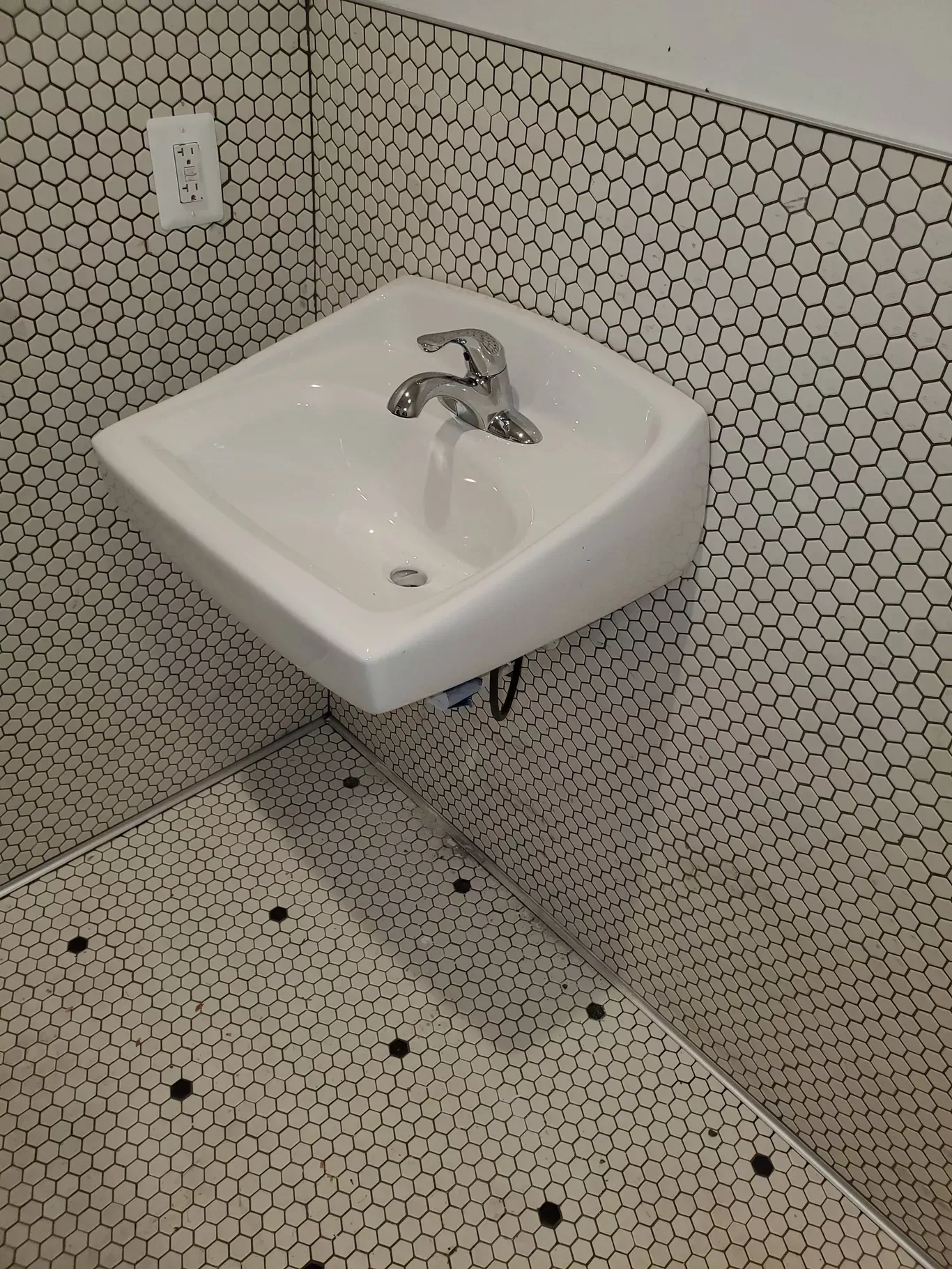 A bathroom sink with a black and white tile floor.