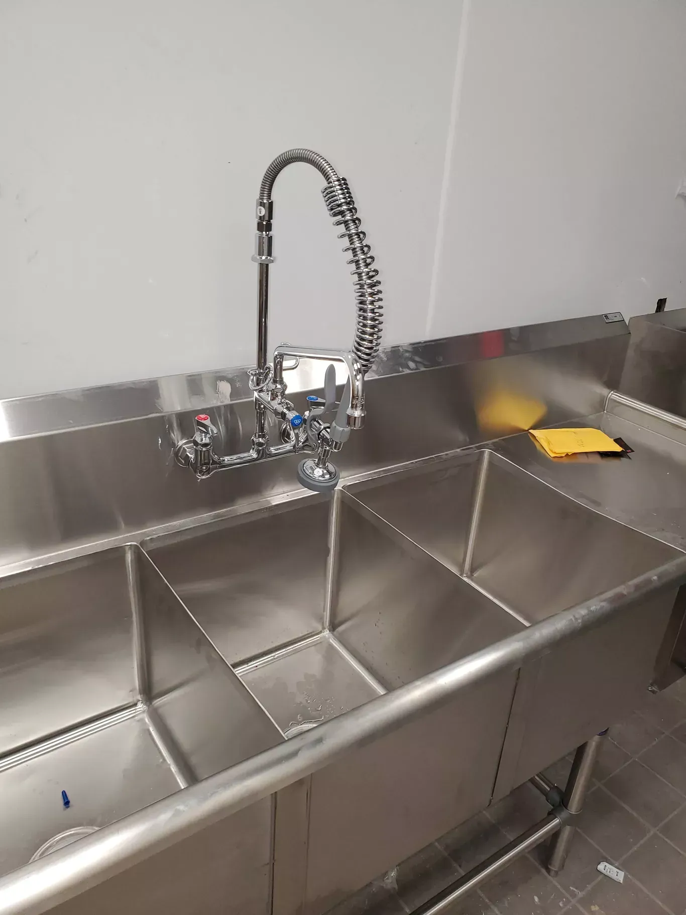 A stainless steel sink with a faucet in a kitchen.
