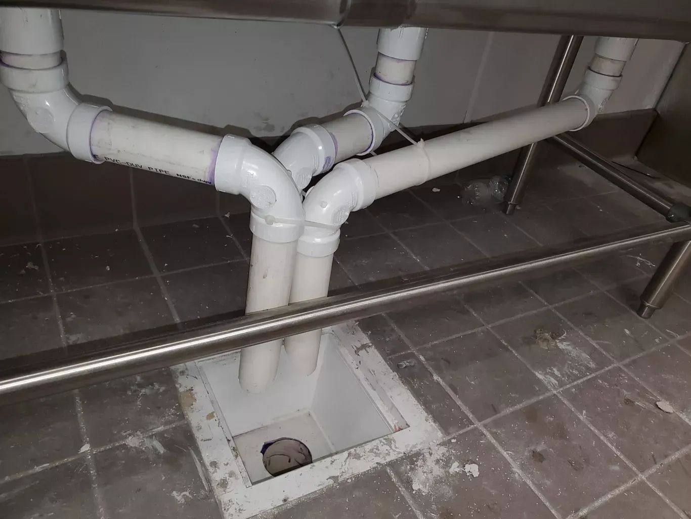 A sink with a hole in the floor underneath it.