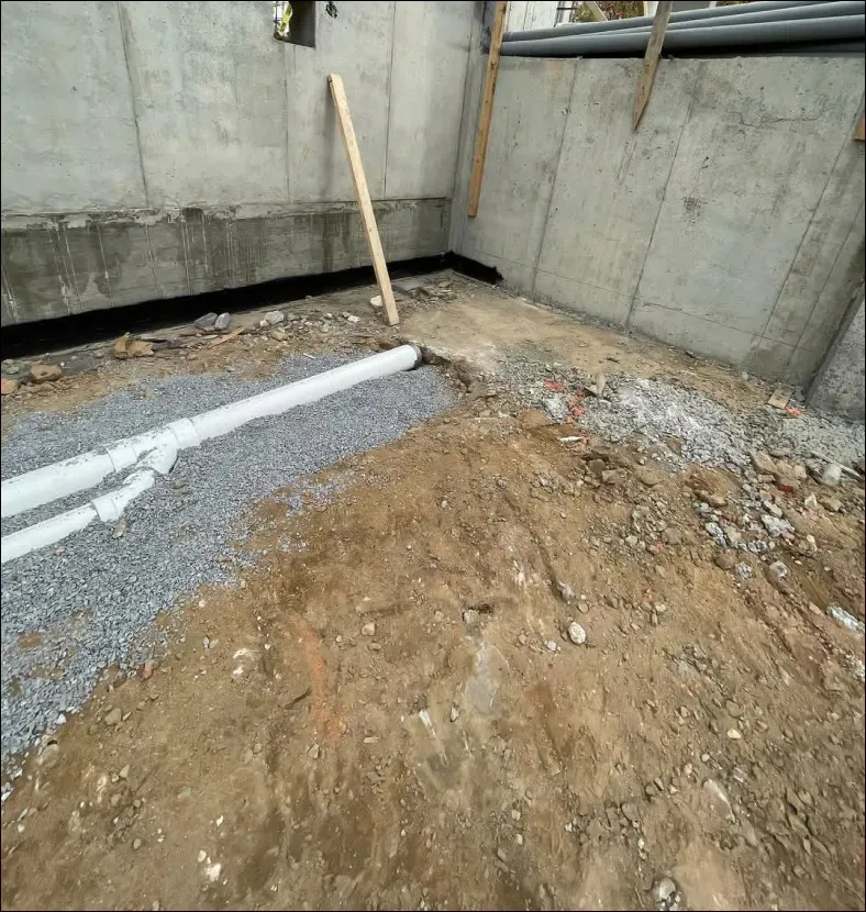 A concrete wall is behind a pile of dirt and rocks