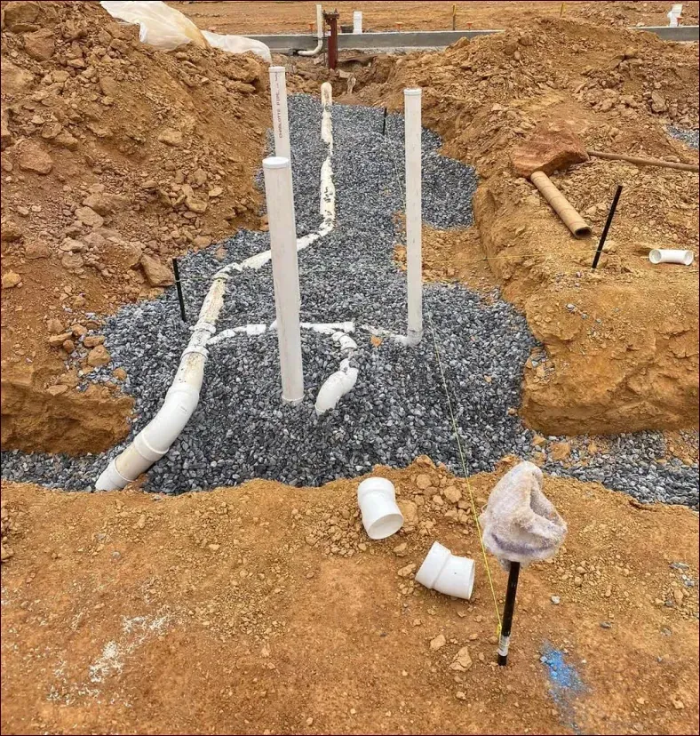 A bunch of pipes are laying in the dirt