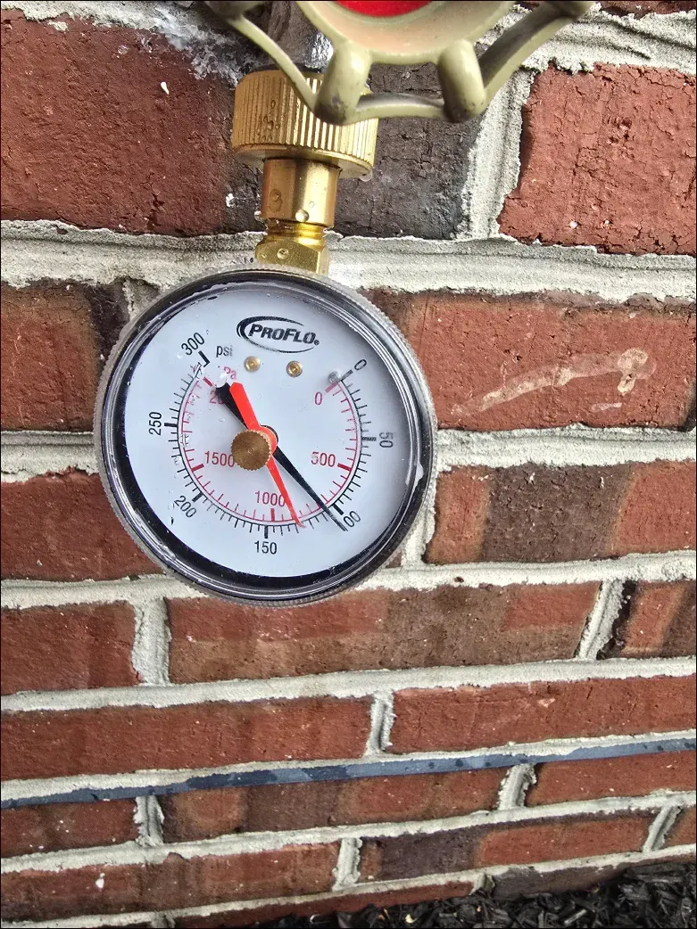 A close up of a pressure gauge on a brick wall