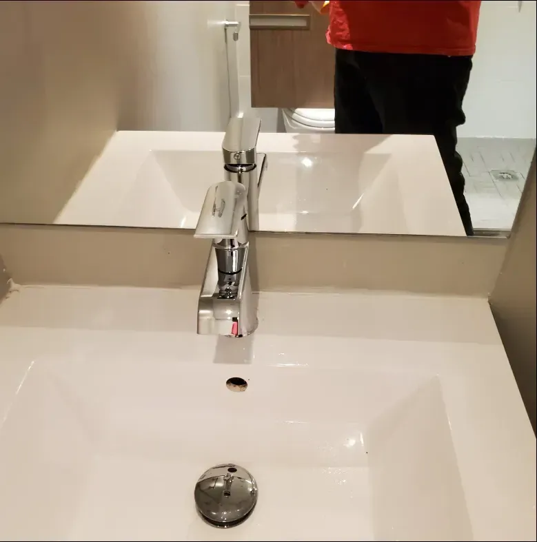 A stainless steel kitchen sink with a faucet on a granite counter top.