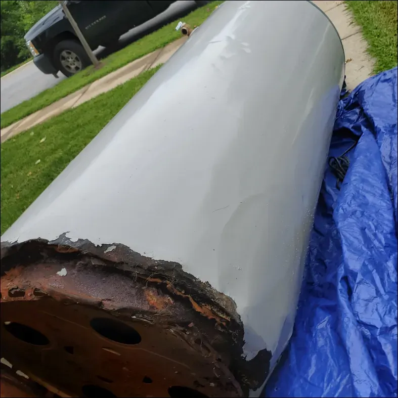A rusty water heater is sitting on a blue tarp