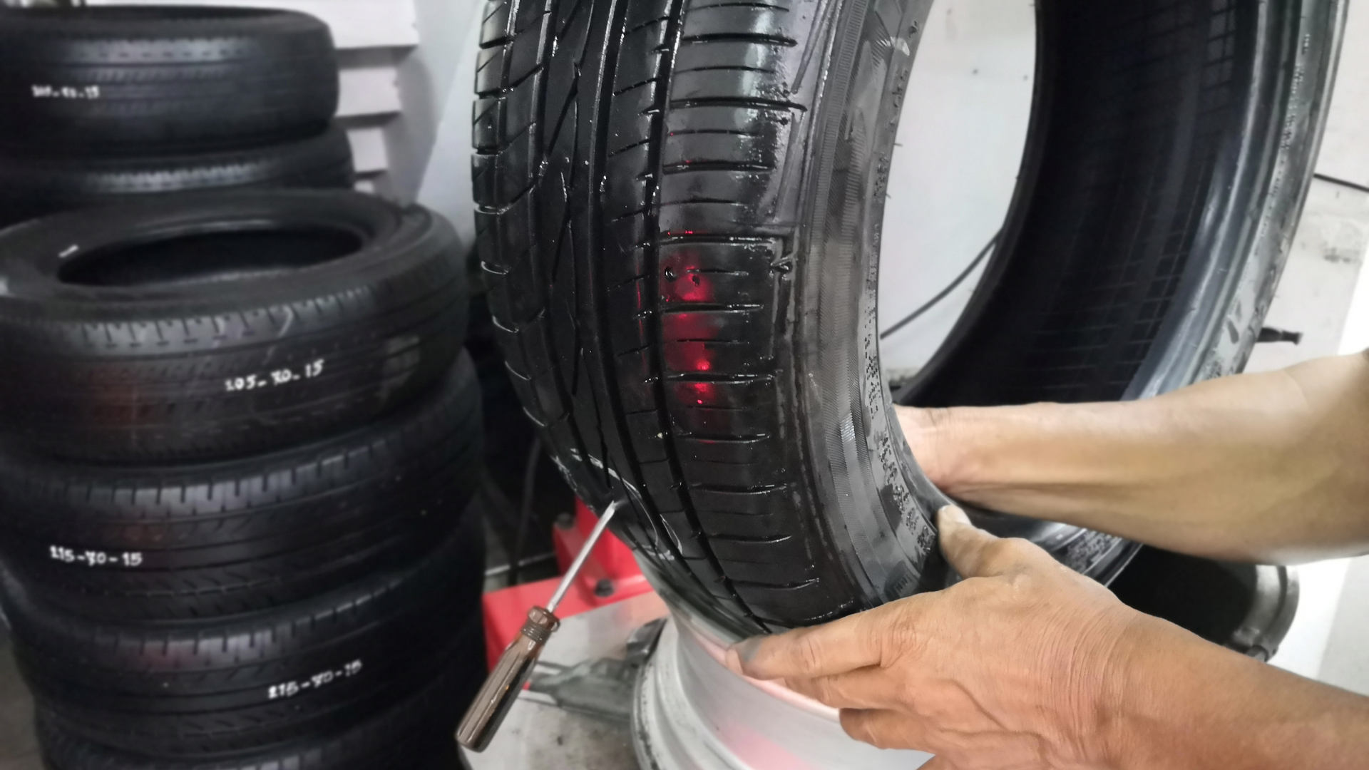 A person is holding a tire in front of a pile of tires.