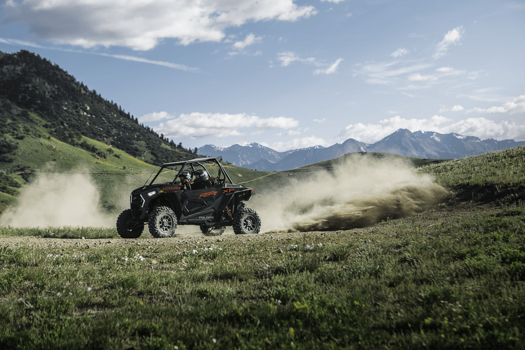 Couple driving Polaris RZR rental on off-road trail
