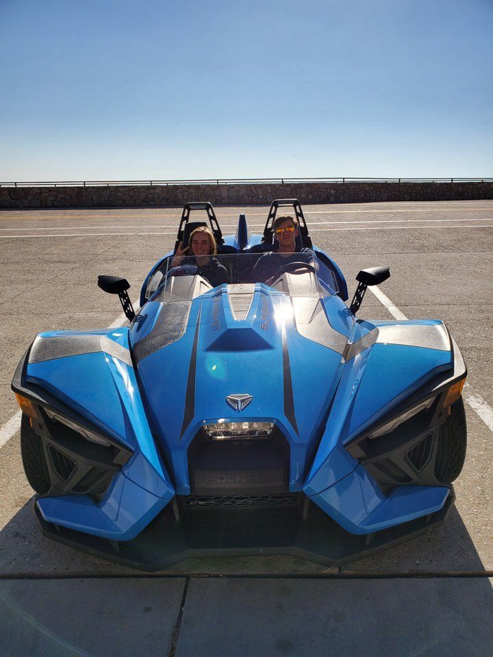 Couple smiling in blue Polaris Slingshot from Tucson Adventure Rentals