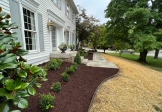 A large white house with a lush green yard in front of it.