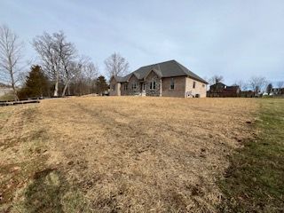 A large house is sitting on top of a dry grass field.