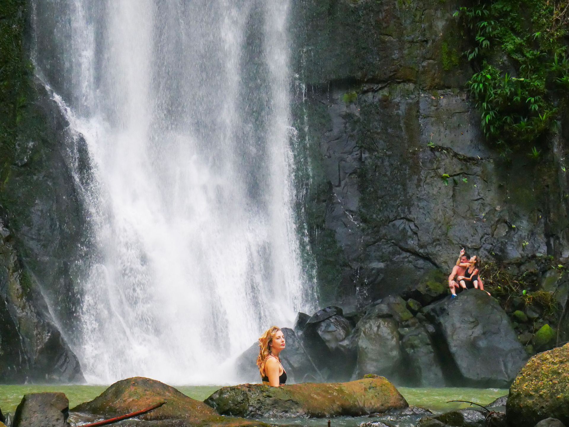 Travelers swimming and relaxing at a tropical waterfall near Puerto Viejo during a Caribe Sur waterfall tour.