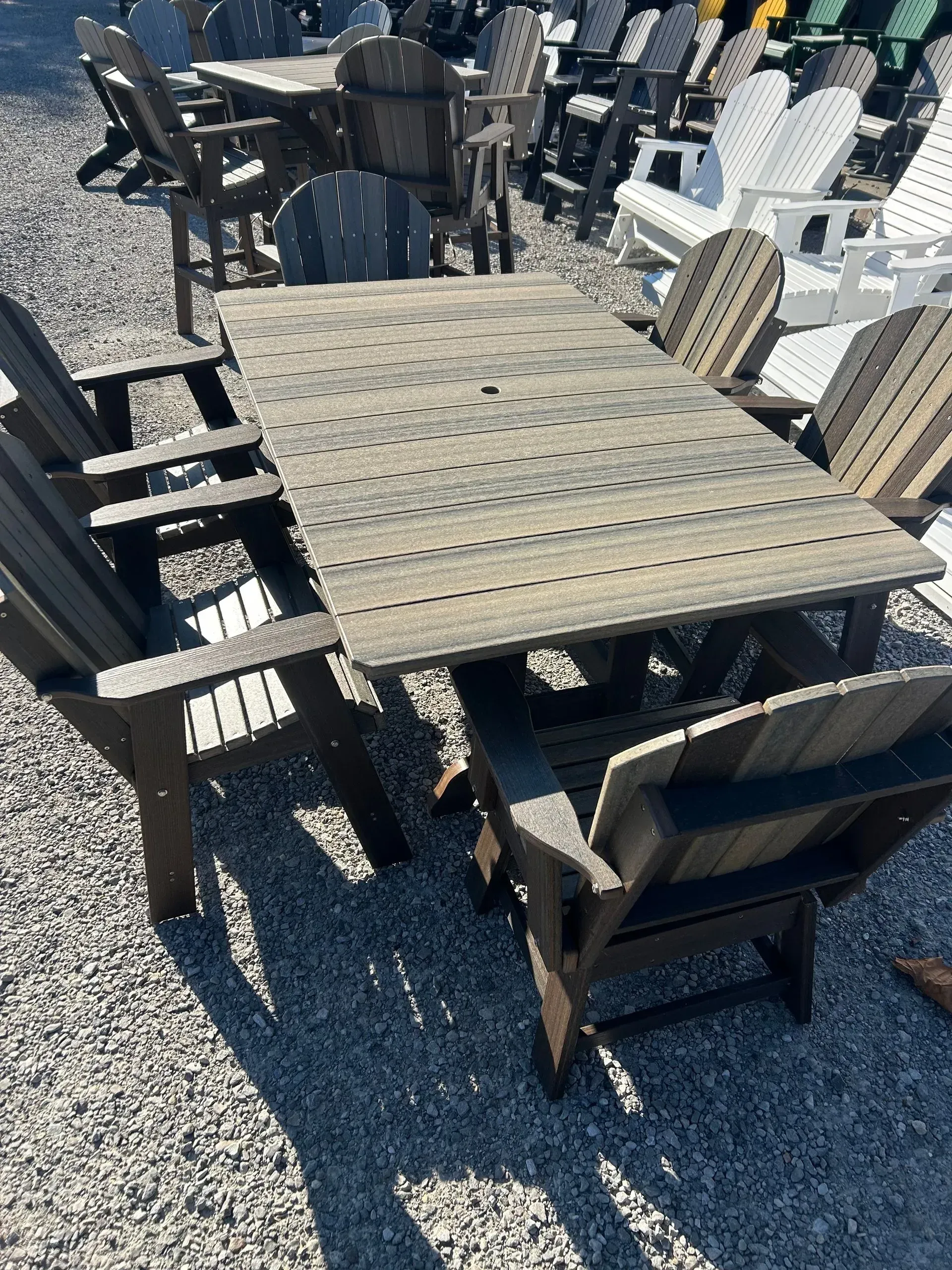 Wooden outdoor dining set with a table and chairs on a gravel surface.