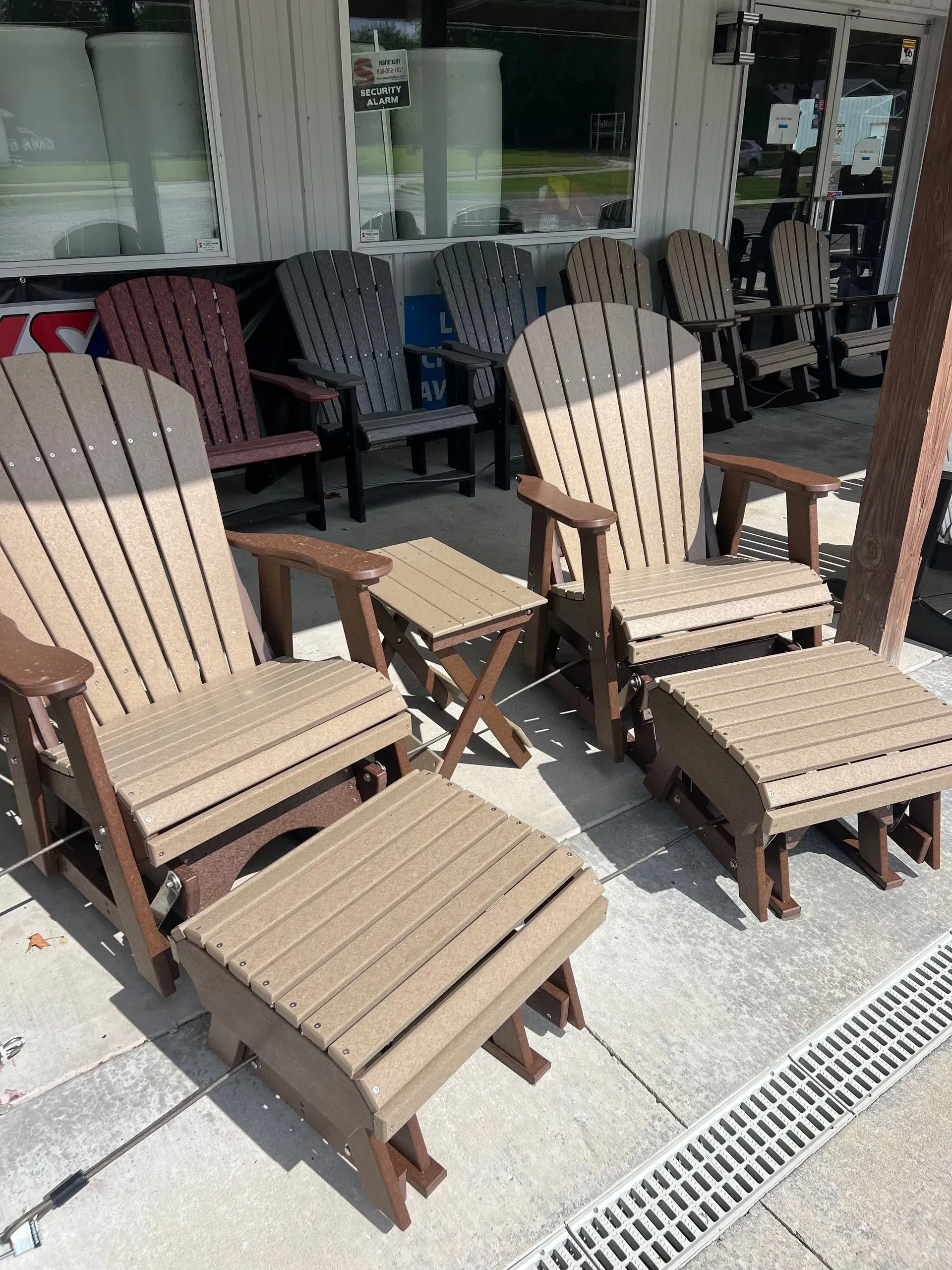 Outdoor furniture display, beige Adirondack chairs with ottomans and a small side table.