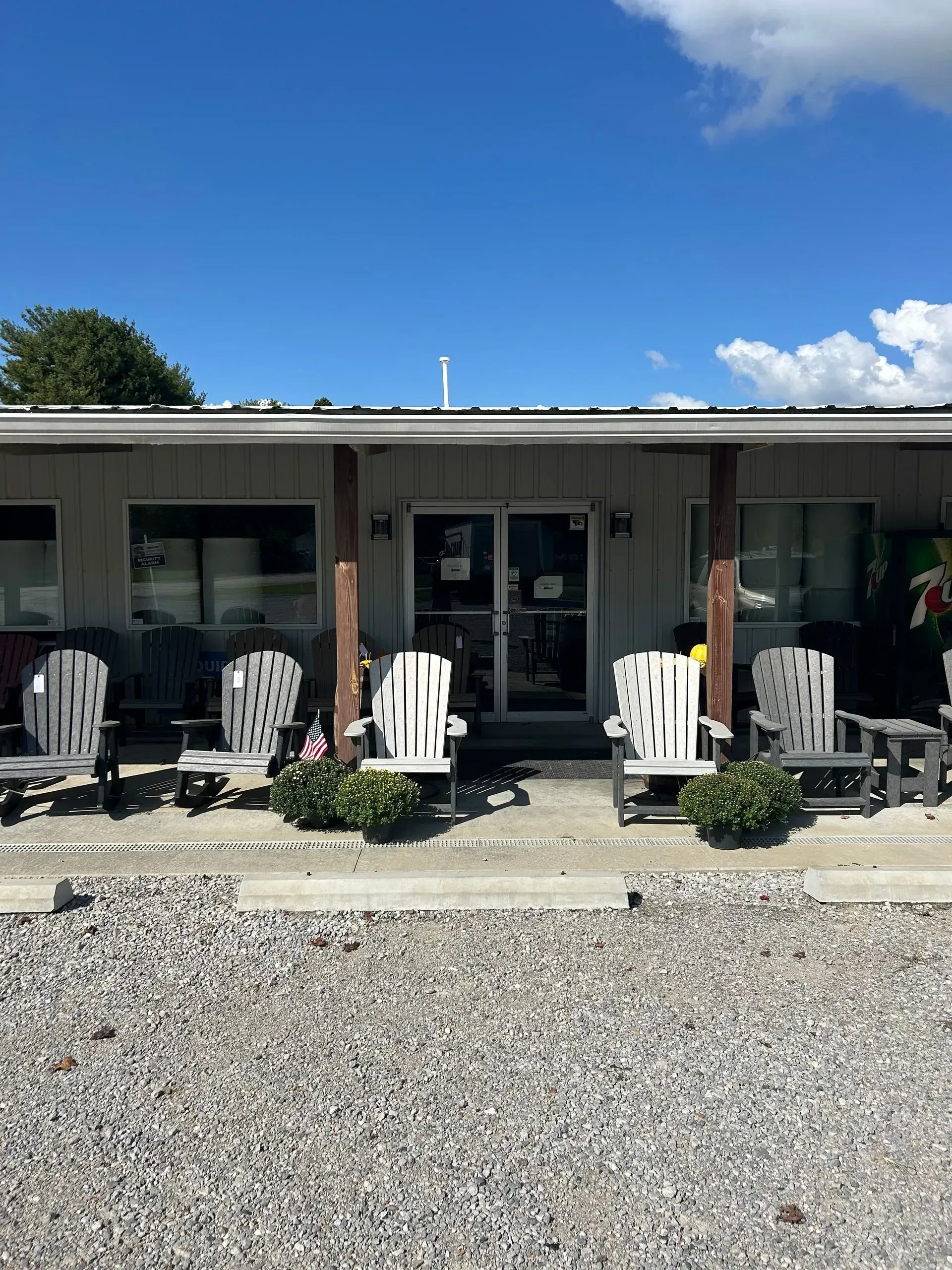 A shop with white Adirondack chairs on the porch. Bright sunny day with blue sky.