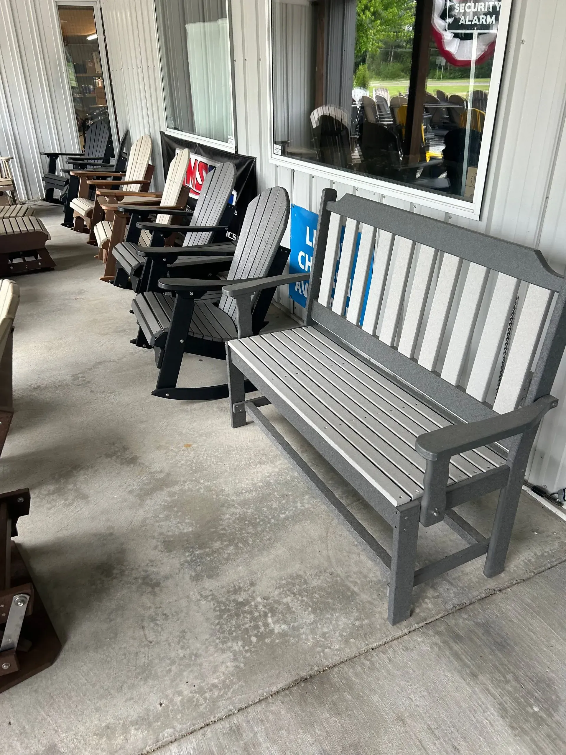 A grey outdoor bench and chairs sit on a concrete patio.